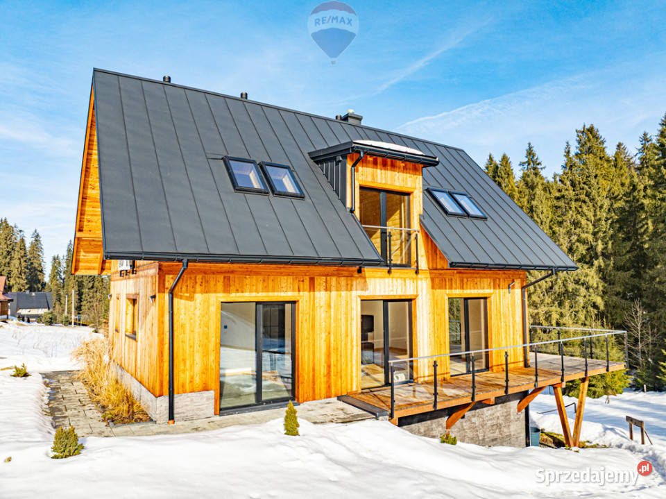 Dom jednorodziny z wiatą w otoczeniu lasu i