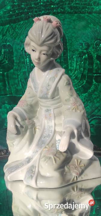 Duża porcelanowa figurka siedzącej gejszy
Wysokość 21 cm 
Po