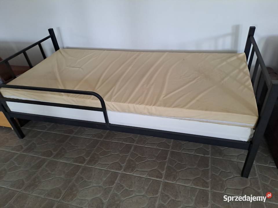 Łóżka piętrowe metalowe z materacami.