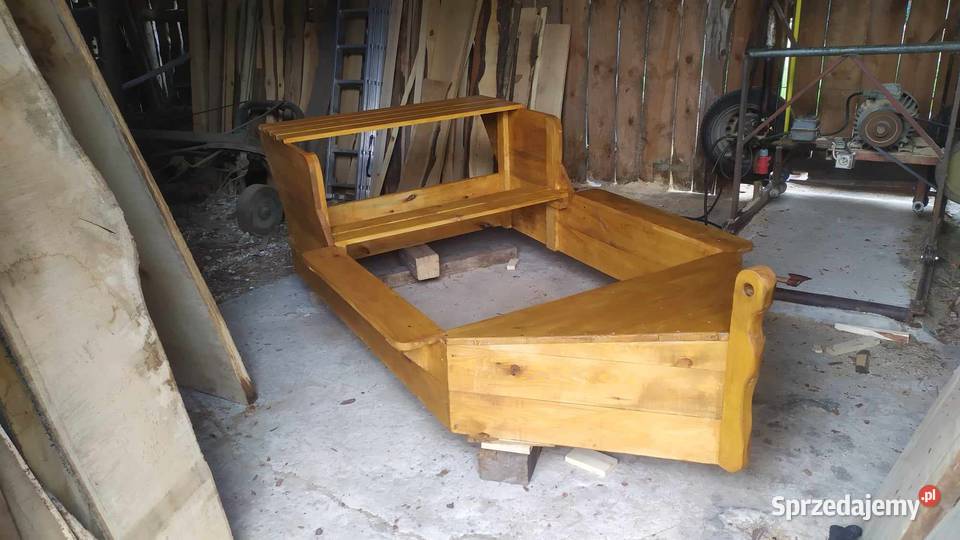 Drewniana piaskownica ze stolikiem w kształcie łódki.