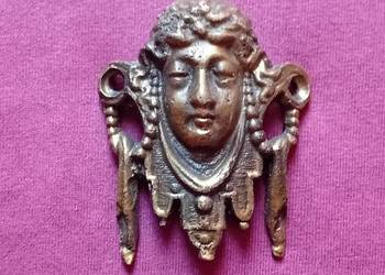 Secesyjne, mosieżne okucie meblowe w formie głowy kobiety.