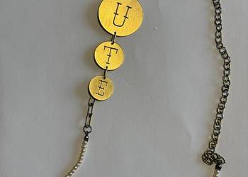 Długi naszyjnik z napisem i koralikami.