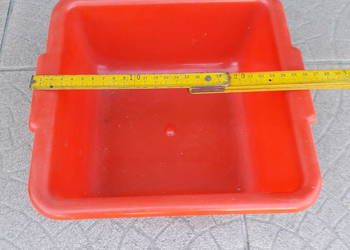 Czerwony plastikowy pojemnik, kwadratowy o boku ok. 25 cm, ok. 10 cm gł.