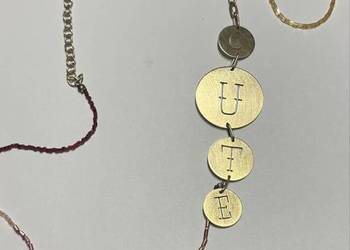 Długi naszyjnik z napisem i koralikami.