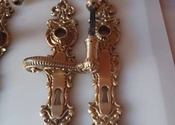 Dwie klamki i dwa szyldy mosiężne.