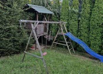 Domek drewniany z huśtawkami i zjerzdżalnią
