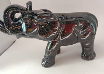 Duży czarny słoń z trąbą do góry i krocząca podstawa