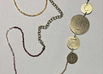 Długi naszyjnik z napisem i koralikami.