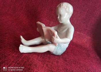 Figurka siedzącego chłopca czytającego książkę. Figurka siedzącego chłopca czytającego książkę.