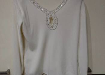 Biały sweter z ozdobną biżuterią w kolorze srebrnym .