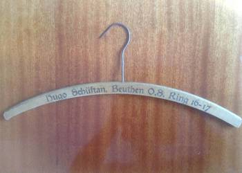 Przedwojenny wieszak drewniany z logo i metalowym hakiem.