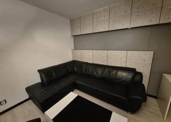 Czarna skórzana sofa z podnóżkiem.